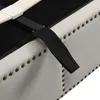 A close-up view of the upholstered side of a bed frame, showing decorative studs and a black strap attached to the frame. Produktbild-Vorschau