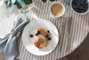 A breakfast setting with pancakes, blueberries, coffee, and cutlery on a striped tablecloth. Náhled obrázku produktu