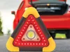 A red car with its trunk open and a warning triangle with LED lights in the foreground. Voir les images du produit
