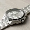 A close-up shot of a silver Casio watch with a white dial, placed on a light wooden surface. Produktbild-Vorschau