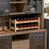A wooden wine rack filled with red wine bottles, placed on a wooden surface in what appears to be a kitchen or bar area. Podgląd zdjęcia produktu