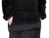A close-up view of a person's hands in the pocket of a black, plush hoodie. Produktbild-Vorschau