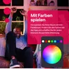 A man is sitting on a couch with his arms raised in celebration, with a pink overlay containing text and a color wheel graphic. Produktbild-Vorschau