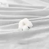 A close-up shot of a cotton boll resting on a white, textured fabric. Podgląd zdjęcia produktu