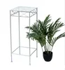 A white metal plant stand next to a potted green plant. Anteprima dell’immagine prodotto