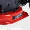 A close-up view of a red lawnmower deck with black components and warning labels. Produktbild-Vorschau