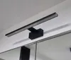 A black LED light fixture mounted on a white wall above a mirror. Produktbild-Vorschau