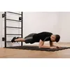 A man is doing a plank exercise with his feet on a wall-mounted pull-up bar. Produktbild-Vorschau