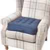 A dark blue tufted seat cushion placed on a beige and blue plaid armchair. Náhled obrázku produktu