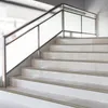 A modern staircase with white tiled steps and a metal handrail with frosted glass panels. Podgląd zdjęcia produktu