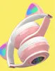 A pair of pink and white cat-ear headphones with LED lights, displayed against a yellow background. Produktbild-Vorschau