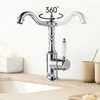 A chrome faucet with a white handle is shown on a countertop next to a tissue box and cups. Produktbild-Vorschau