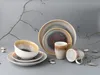 A set of stoneware dishes and mugs arranged on a gray surface with decorative branches and stones. Náhľad obrázku produktu