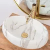 A close-up shot of a marble-patterned vessel sink with a gold faucet. Anteprima dell’immagine prodotto