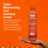 Cantu Moisturizing Curl Activator Cream auf Hand und Schrift auf orangefarbenen Grund Anteprima dell’immagine prodotto