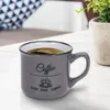 A close-up of a gray coffee mug filled with coffee, placed on a white surface. Náhled obrázku produktu