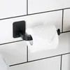 A black toilet paper holder with a roll of toilet paper attached, mounted on a white tiled wall. Anteprima dell’immagine prodotto