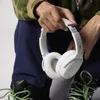 A person holding a pair of white headphones. Náhled obrázku produktu