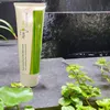 A tube of toothpaste is placed on a stone surface with plants and a waterfall in the background. Voir les images du produit