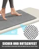 A person's feet stepping onto a gray mat placed on a slightly inclined surface. Produktbild-Vorschau