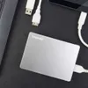 A silver Toshiba external hard drive is connected to a laptop and a smartphone via USB cables, suggesting data transfer or backup. Produktbild-Vorschau