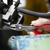 A person's hand is using a pair of pliers to grip a black hose attached to a metal fixture. Voir les images du produit