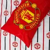 A close-up view of a Manchester United FC duvet cover and pillowcase set, featuring the team's crest and striped pattern. Produktbild-Vorschau