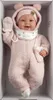 A baby doll dressed in a pink outfit, lying in a box. Podgląd zdjęcia produktu