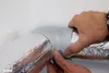 Hands are shown taping a joint between two insulated pipes. Produktbild-Vorschau