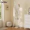A white metal coat rack with clothes and a hat is shown in a room with a dresser and a stool. Náhľad obrázku produktu