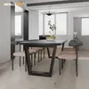 A modern dining room with a black dining table and chairs, set against a white and gray background. Sunlight streams through the blinds, illuminating the space. Náhľad obrázku produktu