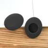 Two black foam ear pads are placed on a wooden surface with a white background. Voir les images du produit