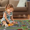 A young girl is playing with a toy car on a colorful rug designed to look like a town with streets and houses. Produktbild-Vorschau