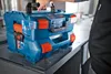 A person is holding a stack of two blue toolboxes with red latches. Anteprima dell’immagine prodotto