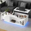 A modern white high-gloss coffee table with a lift-top, integrated storage, and LED lighting, placed in a living room setting next to a gray sofa. Voir les images du produit