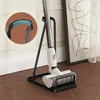 A vacuum cleaner stand with a vacuum cleaner on it, placed on a wooden floor next to a framed picture and a sheer curtain. Produktbild-Vorschau