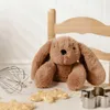 A plush toy bunny sits on a surface with baking ingredients and tools. Voir les images du produit