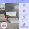 A living room scene with a white radiator heater mounted on the wall, a sofa, a lamp, and a decorative vase of flowers. There is text overlaid on the image with product features. Voir les images du produit