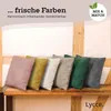 A row of colorful corduroy cushions displayed on a wooden shelf. Produktbild-Vorschau