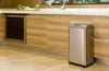 A kitchen scene with a trash can next to cabinets. Voir les images du produit