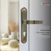 A close-up of a bronze door handle on a white door, with a blurred background of a room interior. Produktbild-Vorschau