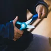 A child's hands are using a pair of turquoise and white safety scissors to cut a piece of blue paper. Náhled obrázku produktu
