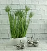 A decorative plant in a pot with two silver cherry figurines in front of a brick wall. Podgląd zdjęcia produktu