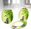 A toilet seat and lid with a bamboo and stone design, presented in a bathroom setting. Produktbild-Vorschau