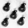 Five black and clear office chair casters are arranged on a light gray wooden floor. Náhled obrázku produktu