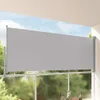A retractable side awning on a balcony, with greenery and sky visible in the background. Náhľad obrázku produktu