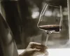 A hand holding a glass of red wine. Produktbild-Vorschau