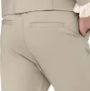 A close-up view of the back pockets of beige pants, with a hand in one pocket. Produktbild-Vorschau
