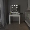 A white vanity table with a lighted mirror is set up in a bedroom next to a bed. Náhled obrázku produktu
