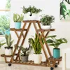 A wooden plant stand with multiple tiers filled with various potted plants, placed indoors near a window. Produktbild-Vorschau